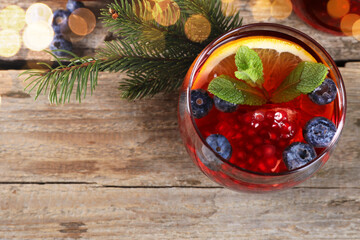 Aromatic Christmas Sangria drink in glass and fir branches on wooden table, flat lay. Space for text