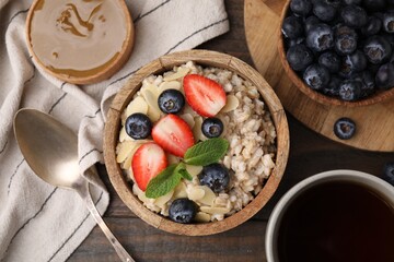 Tasty oatmeal with strawberries, blueberries and almond petals served on wooden table, flat lay