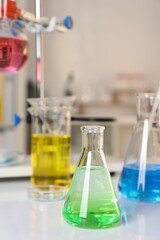 Laboratory analysis. Glassware with different liquids on white table indoors
