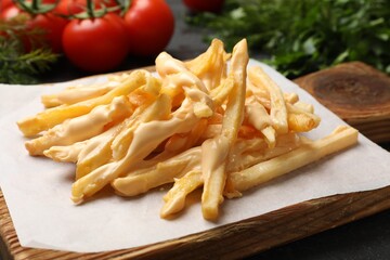 Delicious French fries with cheese sauce on table, closeup