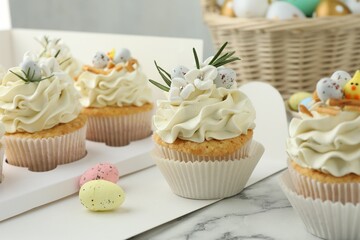 Tasty Easter cupcakes with vanilla cream on white marble table