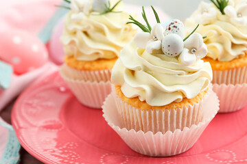 Tasty Easter cupcakes with vanilla cream on table, closeup