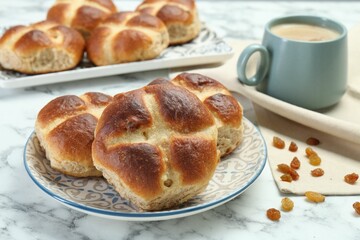 Hot cross buns with raisins and coffee on white marble table