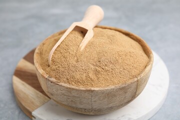 Dietary fiber. Psyllium husk powder in bowl and scoop on grey table, closeup