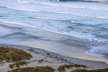 Wundersch&ouml;ner Strand im S&uuml;den von Neuseeland im Sonnenuntergang mit Wellen und Wolken