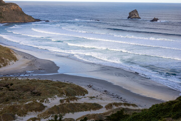 Wundersch&ouml;ner Strand im S&uuml;den von Neuseeland im Sonnenuntergang mit Wellen und Wolken