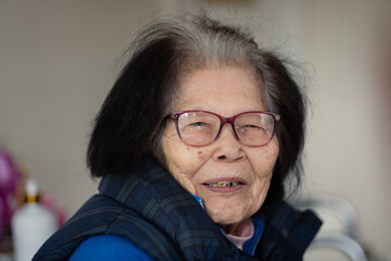 A ninety-something grandmother turns to look at the camera with a smile. She is of Ryukyuan...