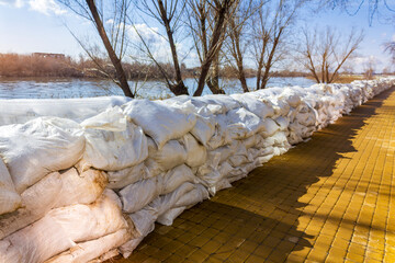A wall of white sandbags has been erected as a barricade for flood protection, representing a defense against natural disasters.