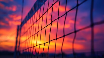 A close-up of a volleyball net against a vibrant sunset sky, with players silhouetted in the background. - Powered by Adobe