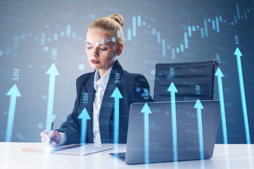 Attractive young woman at desk with laptop and growing blue vertical arrows and candlestick forex...