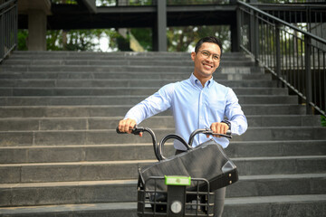 Handsome young businessman with bicycle on a city street. City life and transportation concept
