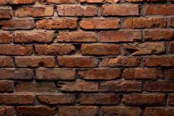A relief wall made of old red brick is illuminated from above. Background. Texture.