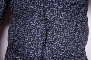 A middle aged slightly over weight man in a blue shirt that is now too small due to the man putting on weight and needed to go on a diet, time for a diet concept.