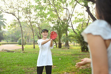 Mother and daughter playing in baseball at public park. Family, sports and leisure activity concept