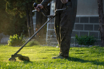Garden worker with lawn mover. Garden works in spring.