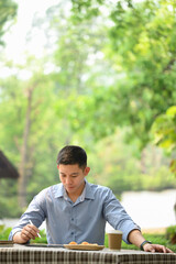 Portrait of young businessman in smart casual wears using digital tablet at outdoor cafe