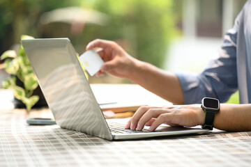 Cropped shot of man holding credit card and shopping online on laptop computer