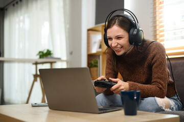 Young caucasian woman in headset holding joystick playing video game on laptop