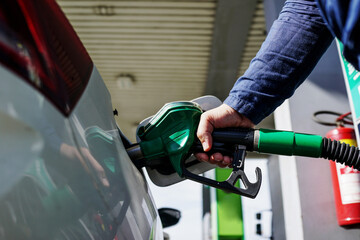 Man driver hand refilling and pumping gasoline oil the car with fuel at he refuel station. Car...