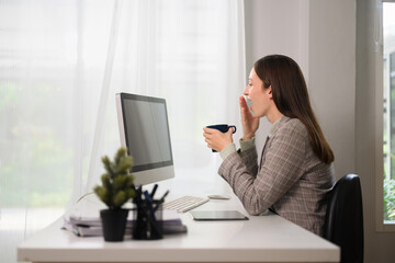 Surprised businesswoman sitting at her workplace and looking at computer monitor