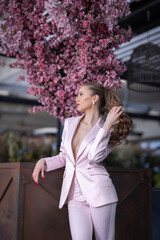 Beautiful young woman in pink suit holding her hair