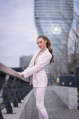 Beautiful young woman in pink suit posing on the street