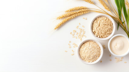 Oat flakes in bowls and ears of wheat on a white wooden background.