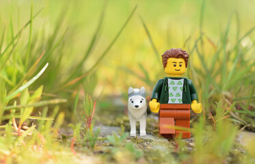 Fototapeta premium Lego minifigures happy boy with dog are walking in the natural green grass. Editorial illustrative image of popular plastic toy.