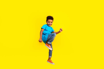 Full body photo of good mood nice small child dressed blue t-shirt jeans flying on black friday isolated on vibrant yellow background