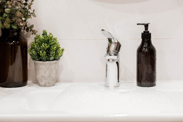 Modern bathroom interior with washbasin and faucet. Panoramic view of a soap dispenser in a bottle...