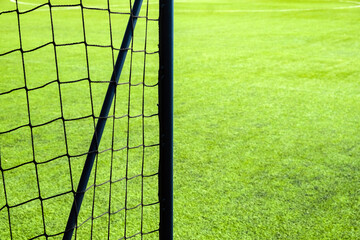 Soccer goal net on green grass field background with copy space.