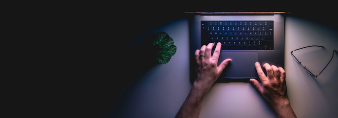 Man using laptop at night, top view, web banner with copy space.