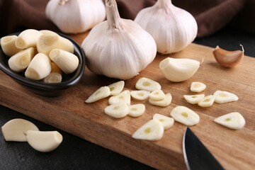 Aromatic cut garlic, cloves and bulbs on dark table, closeup