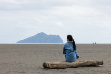Woman sit on the beach and look at the Guishan at Yilan - 786046515