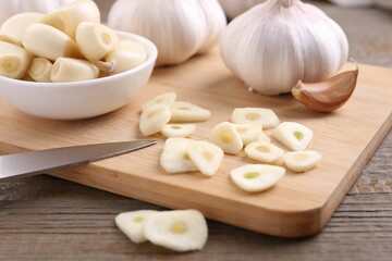 Aromatic cut garlic, cloves and bulbs on wooden table, closeup