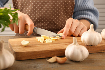 Obraz na płótnie Canvas Woman cutting fresh garlic at table, closeup