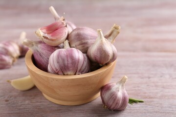 Bowl with fresh garlic on wooden table, closeup