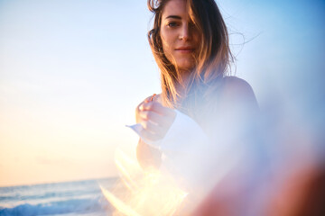 Young woman caught in a dramatic sun flare on the beach, creating an artistic effect