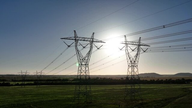 Sun setting behind powerlines in a field