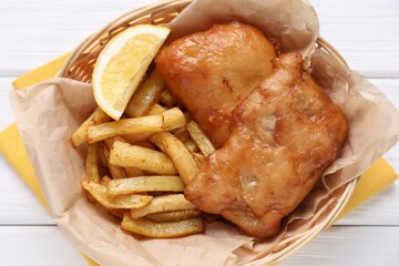 Tasty fish, chips and lemon on white wooden table, top view