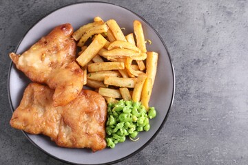 Tasty fish, chips and peas on grey table, top view. Space for text