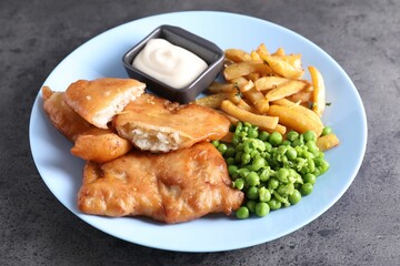 Tasty fish, chips, sauce and peas on grey table, closeup