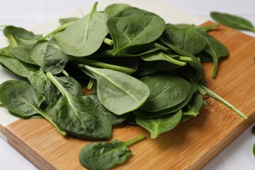 Board with fresh spinach leaves on white table, closeup