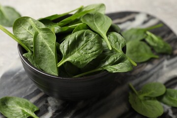 Fresh spinach leaves in bowl on table, closeup