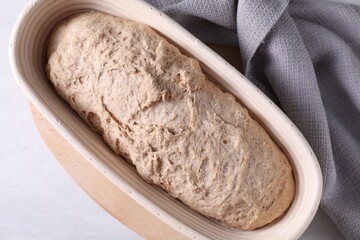 Fresh sourdough in proofing basket on light table, top view