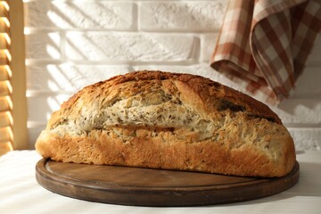 Freshly baked sourdough bread on white wooden table indoors