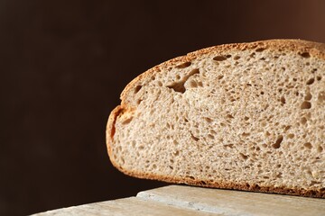 Piece of freshly baked sourdough bread on wooden table, closeup. Space for text