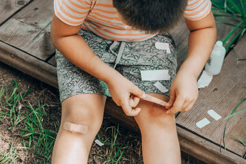 child applies first-aid to a knee scrape, showcasing the brave steps taken towards healing and the...