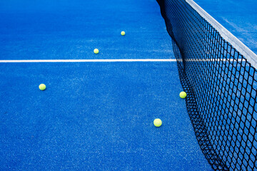 five balls on a blue paddle tennis court near the net, racket sports concept