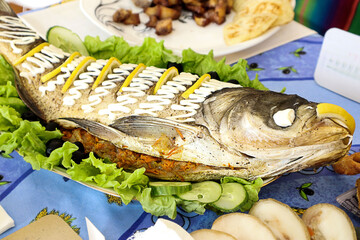 Fish dish: carp on a platter with salad and lemon slices